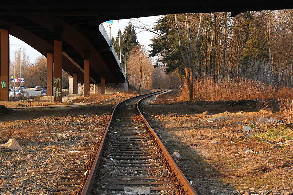 Pohled k severu pod mostem ulice Křižíkovy. Spojovací kolej č. 905 stoupá ze severního zhlaví obvodu staré nádraží k moderní stanici.