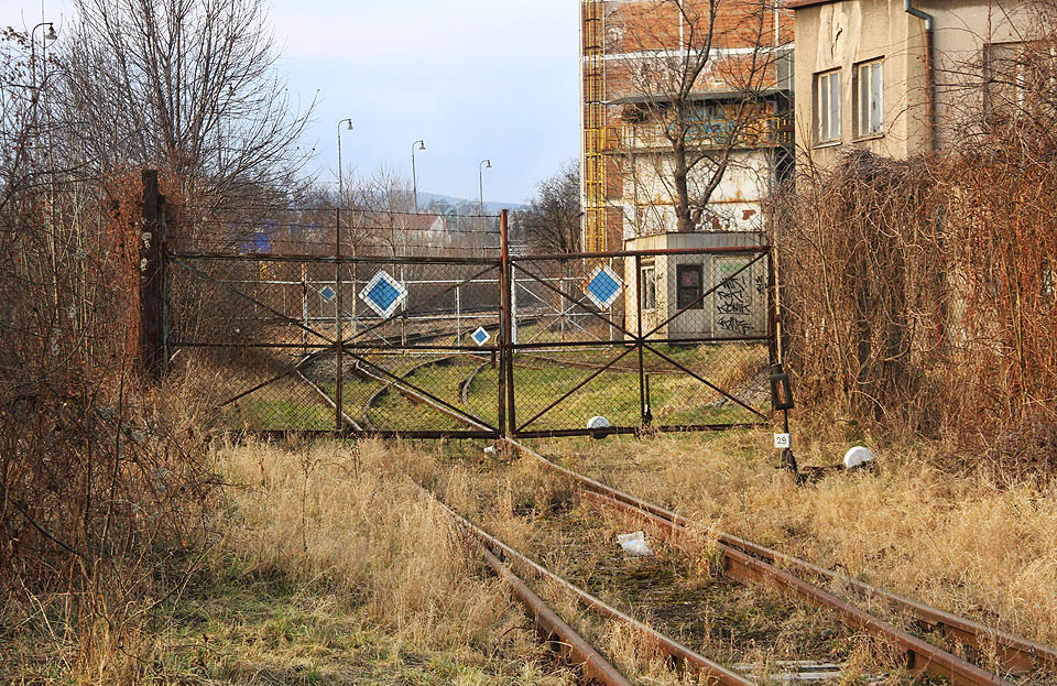 Totéž místo zezadu. Těžko říct, proč ploty a dvojice bran vyťaly z jinak volné trasy vlečky půl křížení a jednu výhybku, které se tak nachází uvnitř areálu. V pořadí jde již o pátou a šestou bránu (od severu) mezi volnou plochou bývalé stanice a vnitřním areálem strojírny.