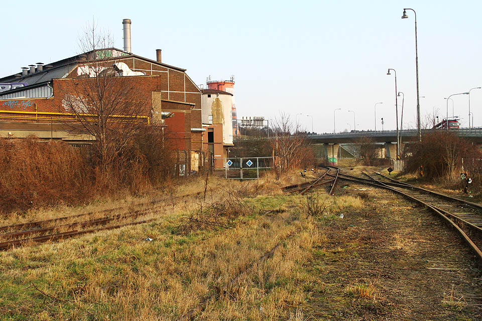 Celkový pohled na jižní zhlaví bývalé stanice se sedmou branou na <a href=/Tema/Vle%C4%8Dka%20Brno-Kr%C3%A1lovo%20Pole%20-%20stroj%C3%ADrna>vlečce do strojírny</a> (vlevo). Kolej uprostřed je bývalá kolej <a href=/Tema/Vle%C4%8Dka%20Brno-Kr%C3%A1lovo%20Pole%20-%20stroj%C3%ADrna>místní dráhy Brno – Tišnov</a>, dnes od matně viditelného zarážedla rovněž součást <a href=>vlečky Královopolské strojírny</a>. Kolej vpravo naopak tvoří <a href=/Tema/Vle%C4%8Dka%20Brno-Kr%C3%A1lovo%20Pole%20-%20tepl%C3%A1rna>nejmladší vlečku</a> bývalé královopolské stanice mířící do teplárny Červený mlýn.