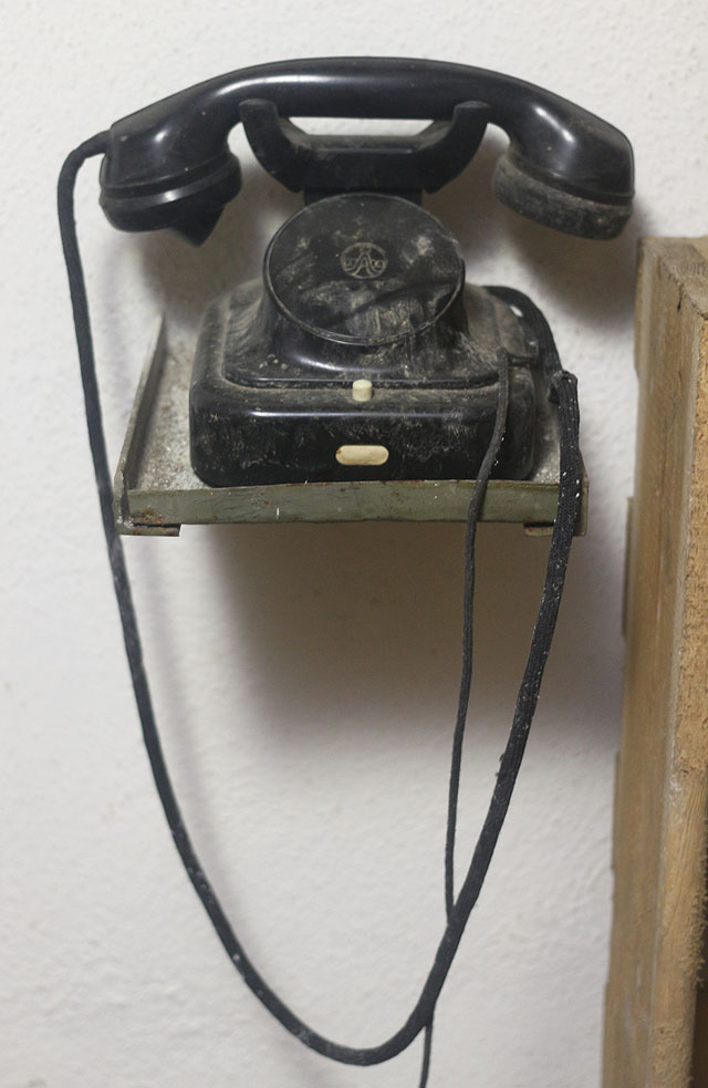 Neoznačený telefon zřejmě sloužil k podzemnímu spojení se zhruba kilometr vzdáleným <a href="/Tema/Velitelský kryt Adamovských strojíren">velitelským krytem</a>, odkud by se v případě války řídily záchranné práce.