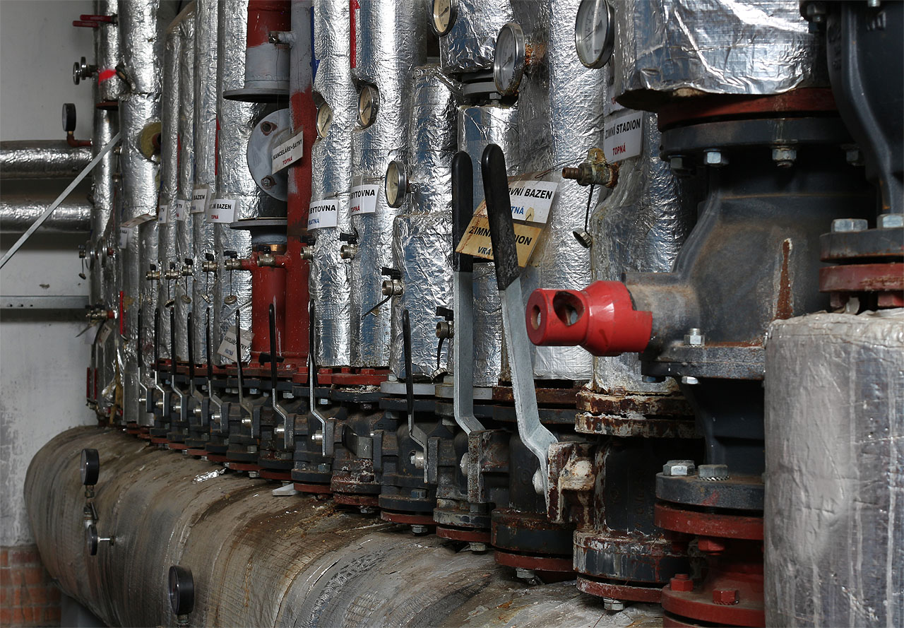 Popisky na horkovdním potrubí dokazují, že kotelna v krytých lázních sloužila půdovně i okolním budovám ve sportovním areálu. Taky proto, že bazén byl na místě jako první.