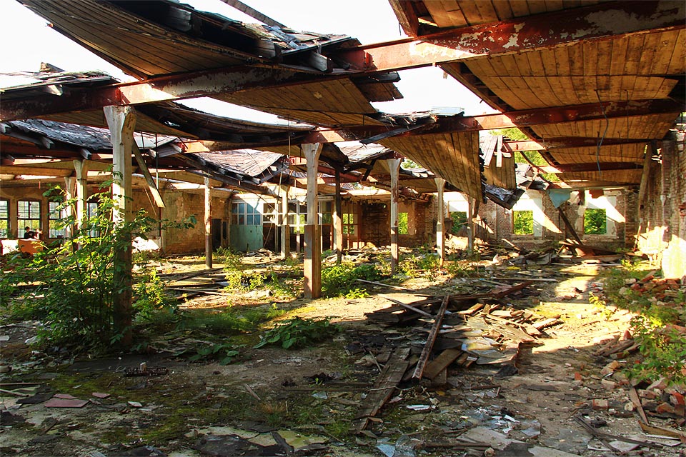 Jednoduchá konstrukce střechy, tvořené dřevěným trámovíjm usazeným na ocelových nosnících, utpěla po zničení prosklených světlíků. Výrobní hala tak navozuje spíš pocit letní zahrady nebo nějaké terasy těsně pod oblohou ze hry <a href=/Tema/Mqachinarium>Machinarium</a>.