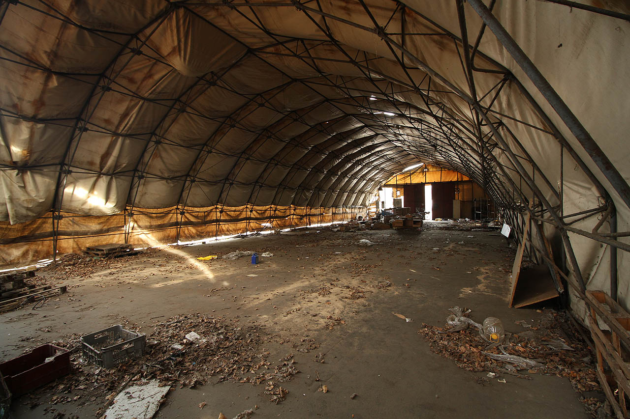 Plachta je převážně neporušená, vrata otevřená, a tak se nám naskýtá pohled na velkorysý prostor. V trošku lepším podnebí by tady mohla být třeba openspace kancelář…