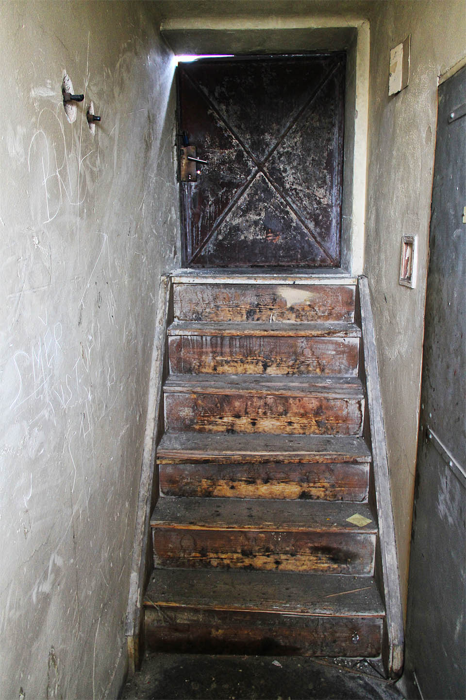 Tahle rezivá dvířka na výšku půl člověka a dřevěné schůdky jsou jediným přístupem na rozsáhlé střechy areálu.
