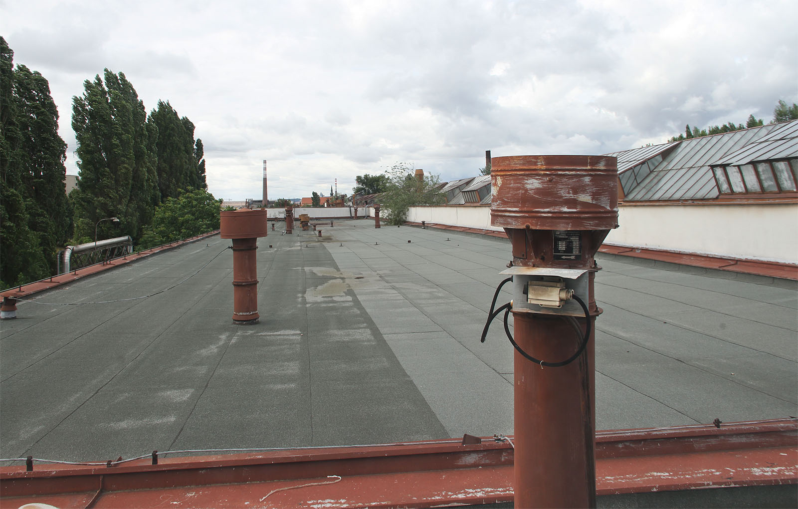 Shora kryje budovu takřka plochá střecha se zajímavě tvarovanými světlíky a výduchy vzduchotechniky.