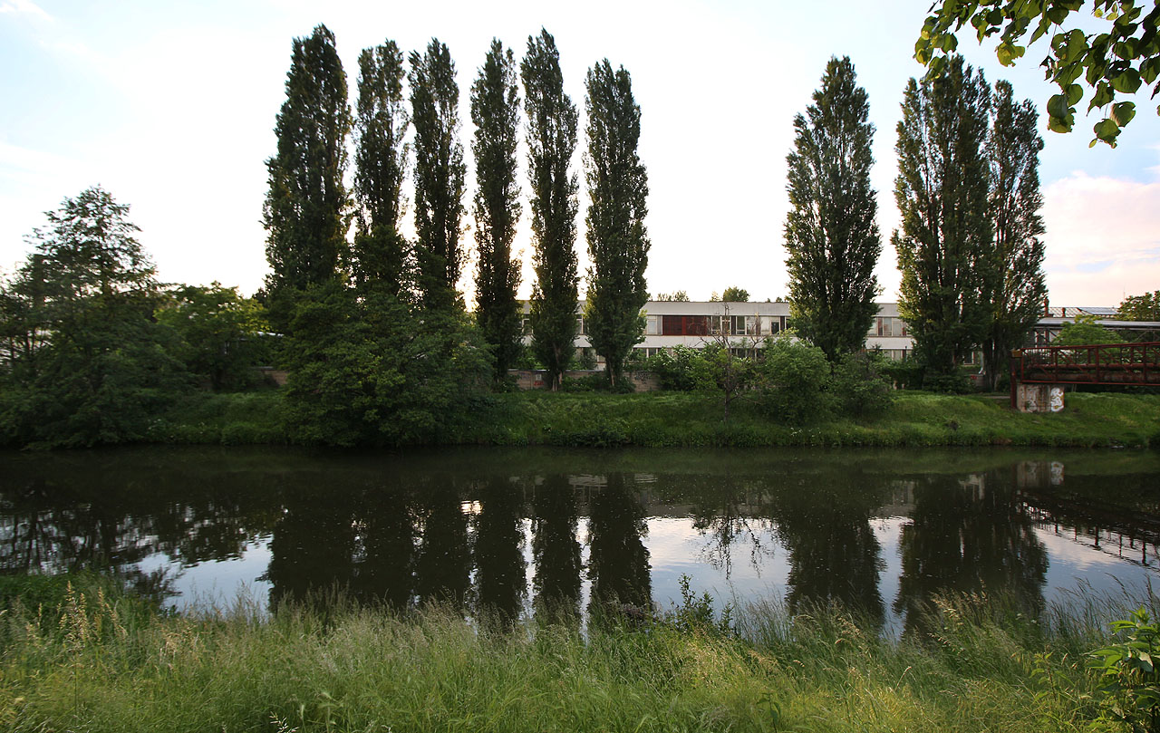 Za hradbou ztepilých topolů je vidět protáhlé východní průčelí motorárny - dvě poschodí sloužila administrativě a dílnám.