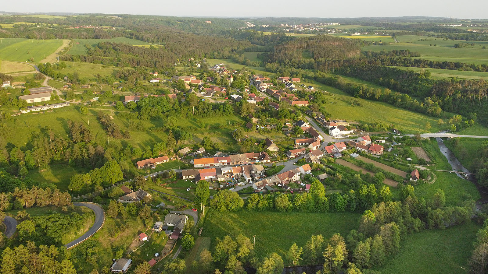 Letecký pohled na Naloučany ze severozápadu. V pozadí je vidět <a href="/Tema/Náměšť nad Oslavou">Náměšť nad Oslavou</a>, vpravo na obzoru chladící věže jaderné elektrárny Dukovany.