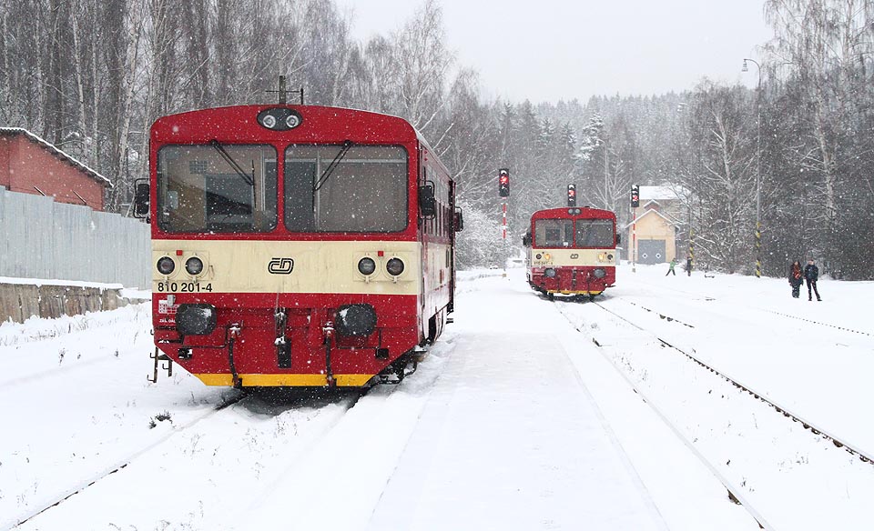 Vzácná chvíle, která se v roce 2015 opakuje pouze dvakrát denně: Na cestující z osobního vlaku č. 17135 z <a href=/Tema/Nov%C3%A9%20Hamry%20%28%C5%BEst%29>Nových Hamrů</a> (vůz 810 041 vpravo) čeká přípojný vlak č. 27112 do <a href=/Tema/Loket%20p%C5%99edm%C4%9Bst%C3%AD%20%28%C5%BEzast%29>Lokte předměstí</a> (vůz 810 201 vlevo).