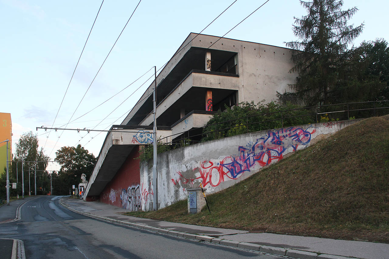 Obchodní centrum letná nepostrádalo jistý druh sídlištní elegance. Robustní nájezdová rampa přecházela ve schodiště a průchod, kterým bylo možné od zastávky překonat hravě tři patra osázená obchody, restauracemi a službami.