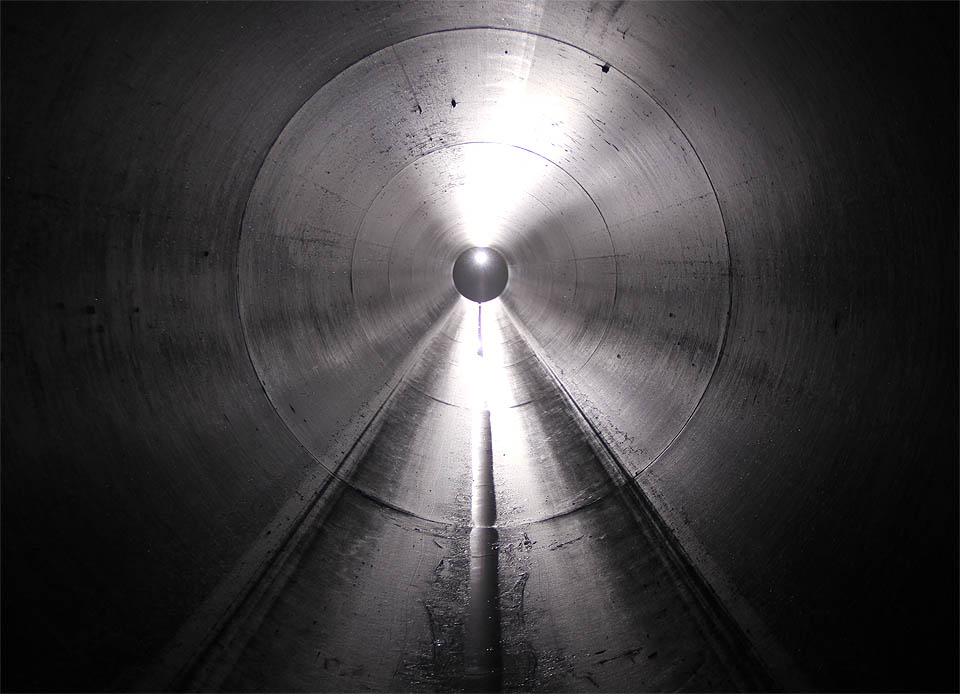 Následuje dlouhá rovná laminátová roura, dostatečně vlhká na to, aby se její stěny v protisvětle elegantně leskly.