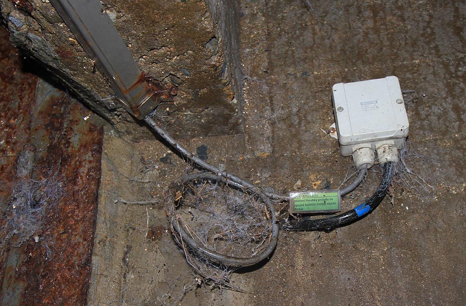 Pozdrav civilizace z povrchu. V osamění tu dlí přístroj pro „měření hloubky proudu ve spojné šachtici (mimo objekt SD16)“.