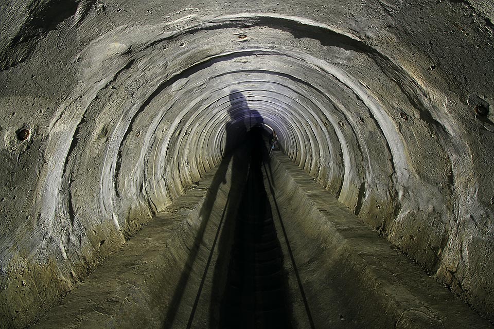 Chodec vrhá na stěny betonové roury podivné stíny.