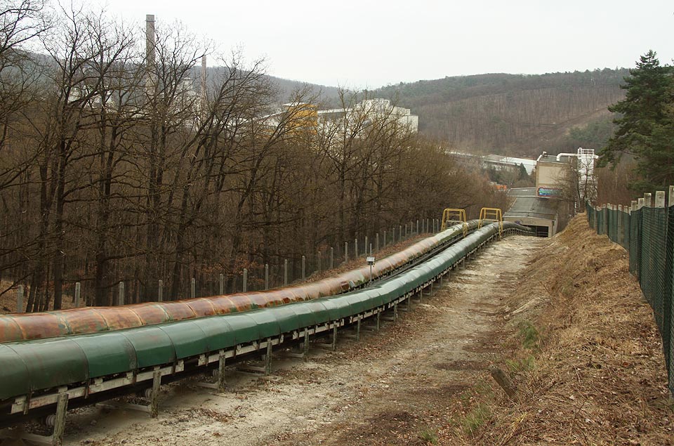 Zhruba v polovině svojí délky se pásový dopravník sklání do údolí potoka Roketnice a blíží se na dohled cementárně a vápence.