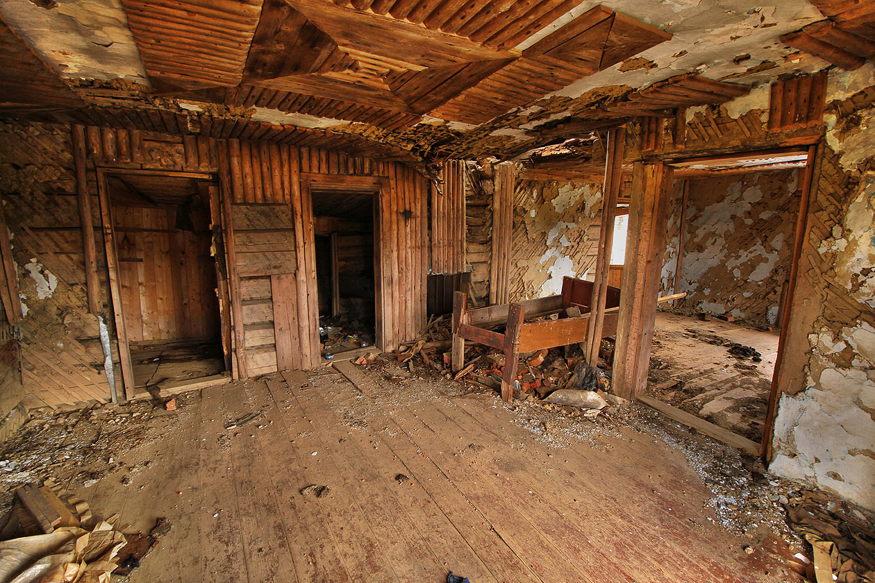 Podleha, strop i stěny, všechno tu bylo ze dřeva, nanejvýš s troškou omítky navrch. Voda prokapávající děravou šindelovou střechou proto dává budově zabrat.