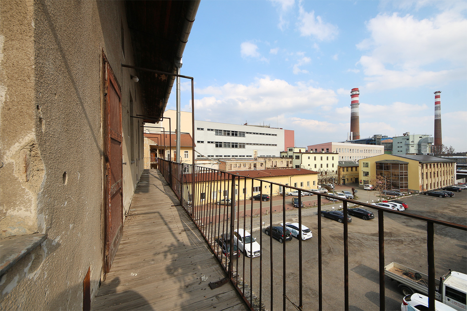 Ze střídmé pavlače se naskýtá romantický pohled přes parkoviště na komíny brněnské teplárny. Té nejstarší a nejzajímavější z brněnských tepláren.