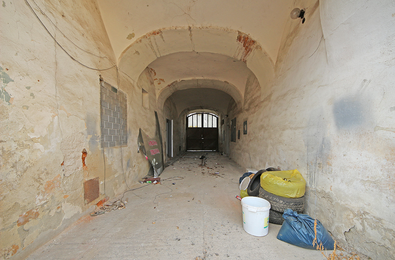 Vstupme nyní průjezdem do útrob domu. Není tu, vcelku očekávatelně, nic, co by polahodilo oku textilního dělníka, navracejícího se po čtrnáctihodinové práci v nedaleké fabrice domů.