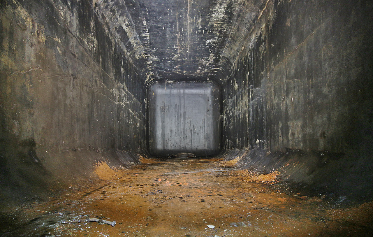 Pohled do betonové nádrže natřené zevnitř dehtovým nátěrem s drceným sklem. Porovnejte s <a href="/index.php?stranka=obrazek.php&obr=Temata/Sklepy_pivovaru_moravia/sklepy_pivovaru_moravia_12.jpg">téměř totožnými tanky</a> pod zaniklým pivovarem Moravia v Brně.