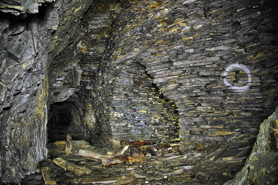 Na protější straně je dobře vidět typický tvar chodby vystavěné nasucho z břidličného odpadu a vyztužené trámci v horní části jako ochrana před padajícími bloky horniny.