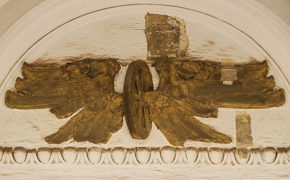 Jako by perutě okřídlených kol nad vchodem jaksi trpěly únavou.