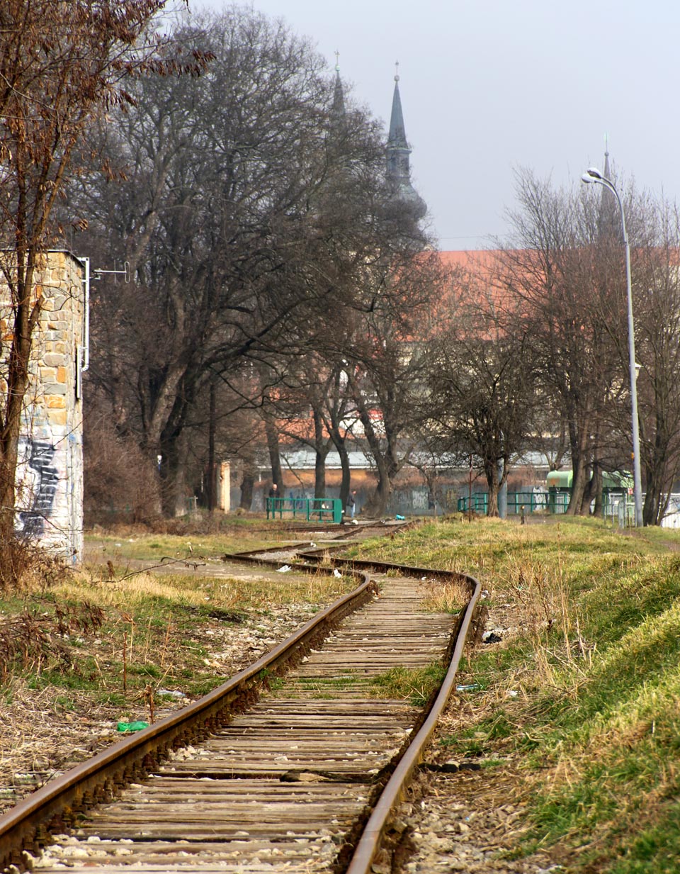 Místo zrušeného nákladiště Radlas na <a href=/Tema/Brno-%C5%BDidenice%20-%20Svitavsk%C3%A1%20pob%C5%99e%C5%BEn%C3%AD%20dr%C3%A1ha>Svitavské pobřežní dráze</a>. Při pohledu k severu jsou v dálce vidět věže kostela Nanebevzetí Panny Marie, naproti kterému stávala do poloviny 20. století stanice <a href=/Tema/Brno-Z%C3%A1brdovice%20%28%C5%BEst%29>Brno-Zábrdovice</a>.