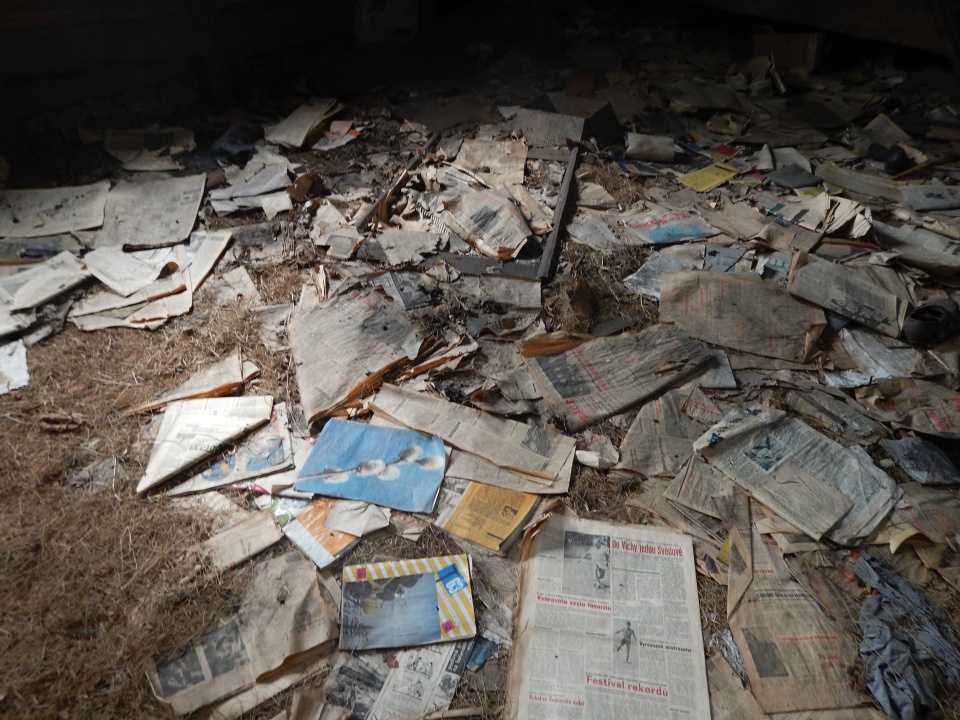 Nikým nepovšimnuté rozházené noviny, časopisy pohlednice i fotky.