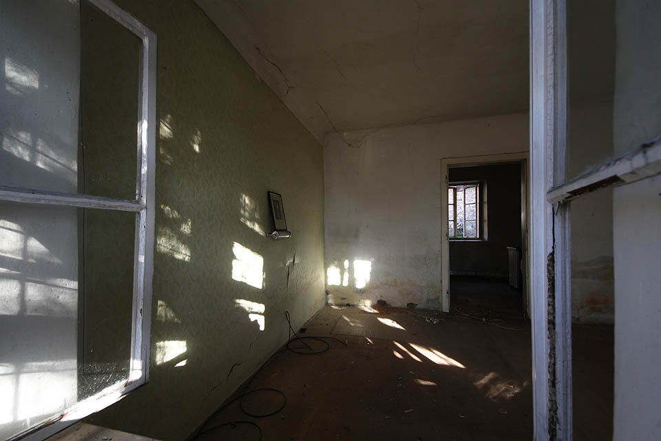 Jako mlčenlivé memento zůstala v obývacím pokoji opuštěného domu nad futuristickou lampičkou fotografie jeho někdejších obyvatel a snad i majitelů. Co by asi na současný stav řekli, kdyby byli naživu?