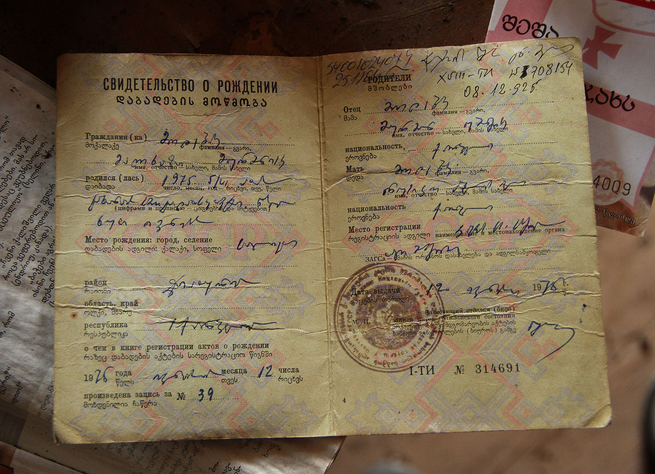 Jméno obyvatele domu narozeného v roce 1975 si může každý přečíst v zapomenutém rodném listě. Pokud ovšem zvládne přelouskat psací abecedu mchedruli. Rodných listů a maturitních osvědčení je tu několik a snad jen původní obyvatelé domu ví, proč si je před léty neodnesli s sebou. Jméno obyvatele domu narozeného v roce 1975 si může každý přečíst v zapomenutém rodném listě. Pokud ovšem zvládne přelouskat psací abecedu mchedruli. Rodných listů a maturitních osvědčení je tu několik a snad jen původní obyvatelé domu ví, proč si je před léty neodnesli s sebou.