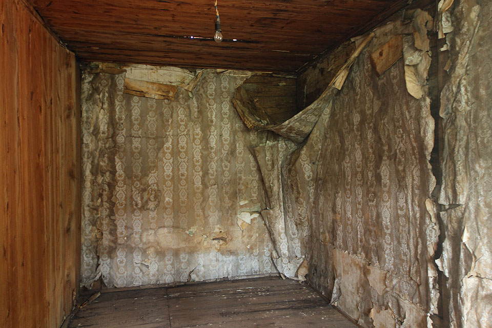 Ložnice či dětský pokoj se zpuchřelými tapetami odhaluje prohnilým otvorem ve stropě nedokonalosti prejzové střechy. Ložnice či dětský pokoj se zpuchřelými tapetami odhaluje prohnilým otvorem ve stropě nedokonalosti prejzové střechy.