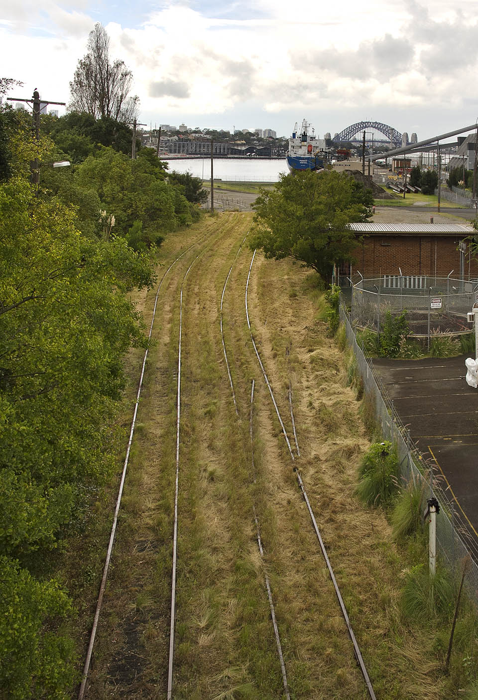 Dvojkolejná trať pokračující směrem k bývalé nákladní stanici White Bay se zrušenou odbočkou severní větve přístavní vlečky na Glebe Island.