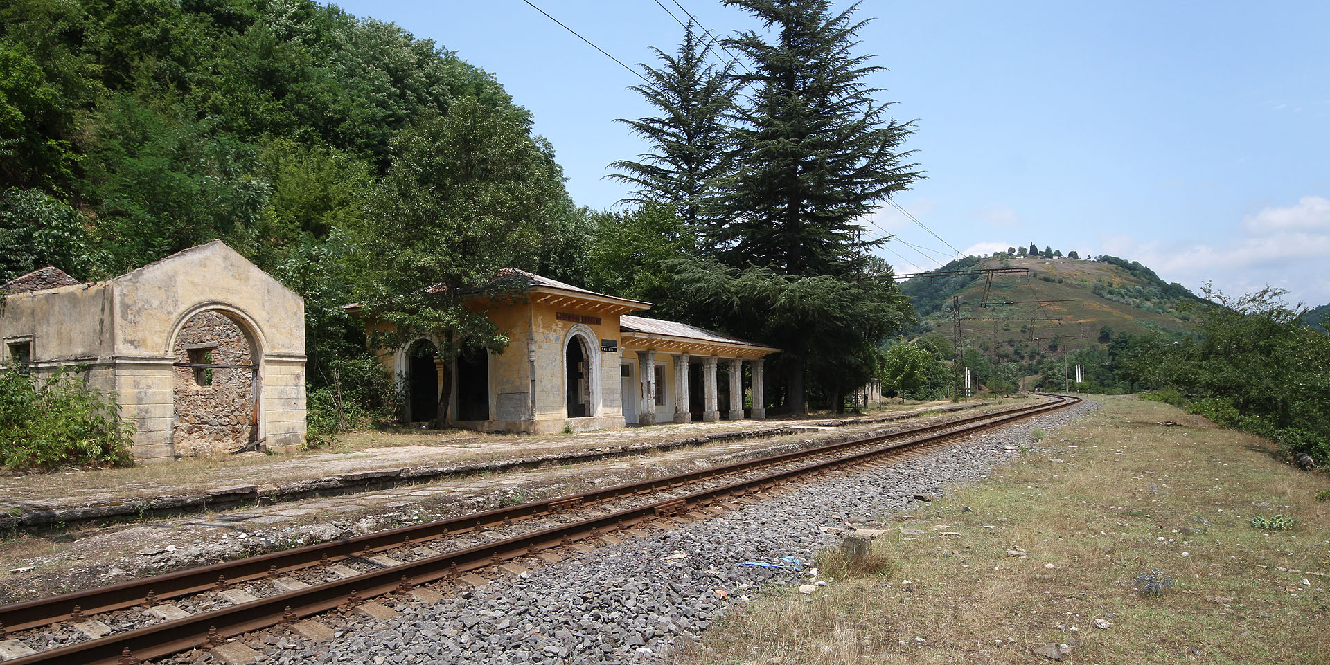 Stavba na fotce vlevo pravděpodobně sloužila jako původní staniční budova od roku 1895, kdy byla dráha vystavěna. Romantizující budova ve stylu stalinského baroka je zřejmě mladší a odhadnout její původ lze do 50. let 20. století.