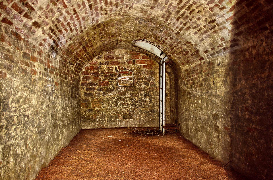 Pohled zpět do hlavní místnosti současného sklepení (k jihozápadu). Tubus s žebříkem byl proražen v rámci sanace provedené v roce 2002 po objevení sklpů pod Orlí ulicí.