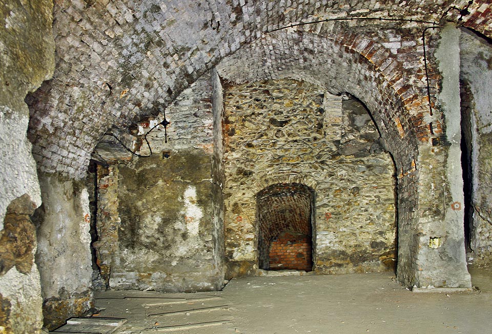 Výškově, stranově i materiálově členitý labyrint podzemních chodeb a sklepů odpovídá svému původu coby sklepení pod několika jednotlivými měšťanskými domy z románského až gotického období. Domy byly navíc později sklepením propojeny pod dlažbou náměstí s budovami na jeho protější straně.