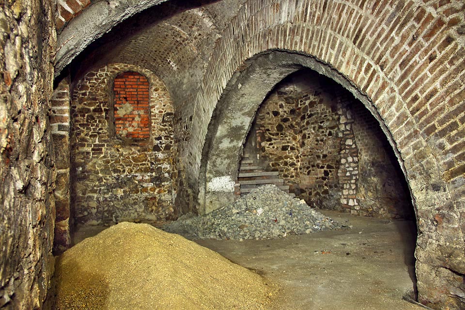 Hromady písku a štěrku připravené na další betonování vypadají čerstvě. Ve skutečnosti tu ale čekají na dělníky už skoro 30 let. Za hromadou štěrku vpravo je vidět světlejšími kameny zazděnou bývalou chodbu pod Římské náměstí.