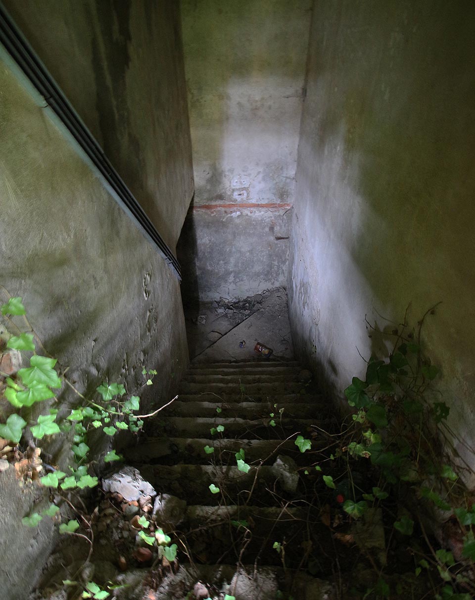 Za nenápadnou mříží se ukrývají strmě klesající schody kamsi blíže ke středu Země.