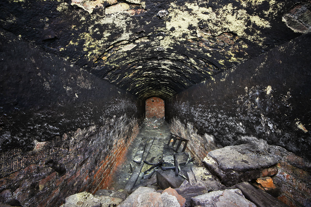Poměrně hluboko v podzemí se nachází také další spojovací chodba, mířící tentokrát k západu. Zajímavá je nejen neobvyklou černou omítkou na cihlových stěnách, která snad měla vylepšit izolační schopnosti chodby, ale také moderní zazdívkou na konci. Tím zřejmě procházela do dalších sklepení, tentokrát za domem č. 66.