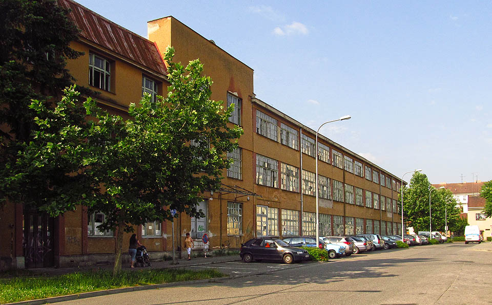 Tak vypadala ulice U Červeného mlýna ještě v roce 2014. Zachováním a opravou prosklené protofunkionalistické fasády mohlo vzniknout působivé městské zákoutí odkazující k industriální historii města Brna. Namísto toho vyrostly v ulici pěkné, leč fádní, téměř typové domy, které se podobají bezcharakterním stavbám kdekoliv jinde na zeměkouli.