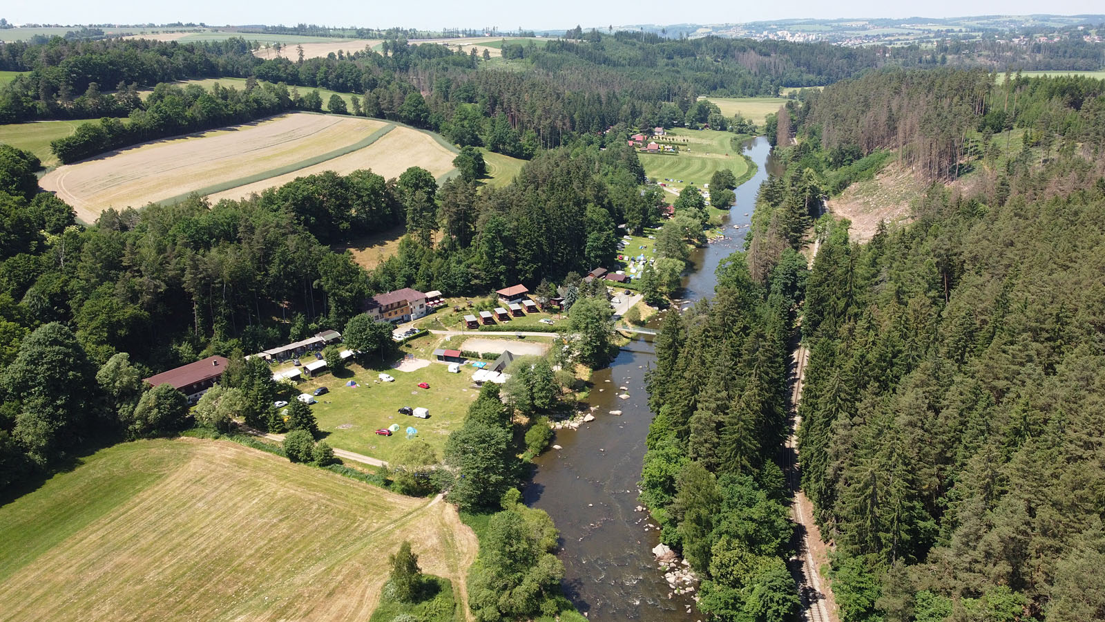 Celkový pohled na Stvořidla. Vodácký kemp, tábořiště, hospodu, rychleji porudící úsek řeky a železniční zastávku, které všechny nesou stejné jméno.