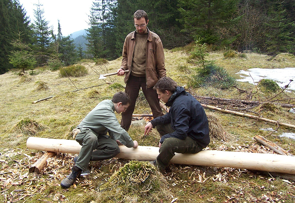 Čáp se sekerou čeká, až mu vrchní měřák s pomocníkem narýsují místo pro začátek opracování jedlového kmene.