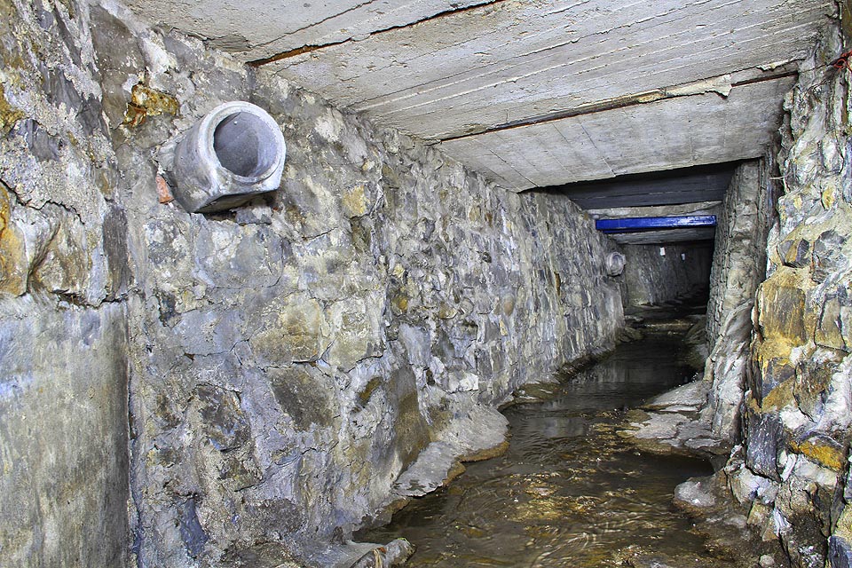 Následuje část s kamennými zdmi a členitým dnem. Pravděpodobně dřív nemívala strop a potok tady protékal mezi zahradami v otevřeném korytu.