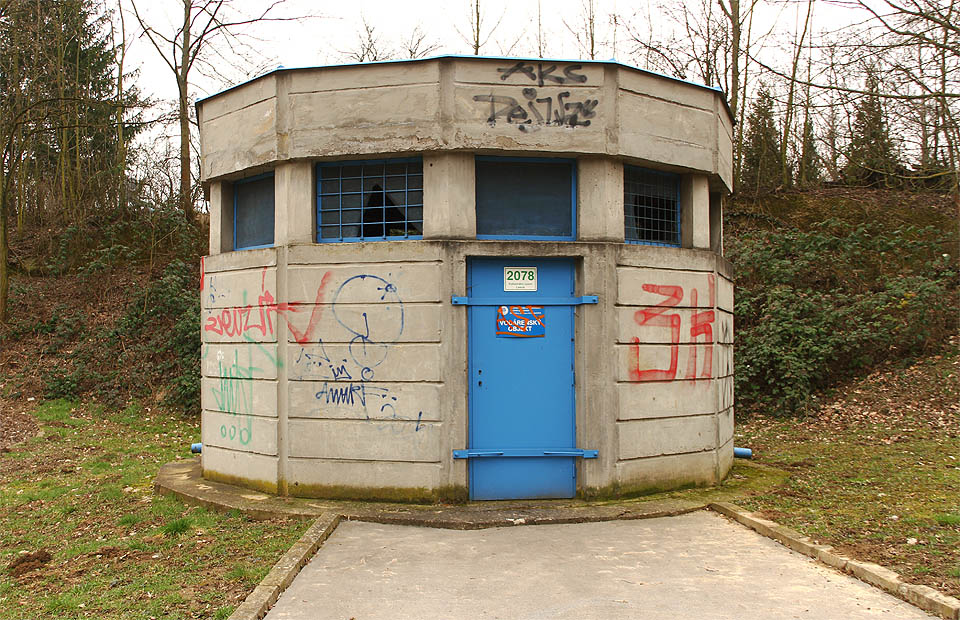 Druhá n-úhelníková betonová budova nad schodištěm do nitra země se nachází pod Divišovou kolonií.