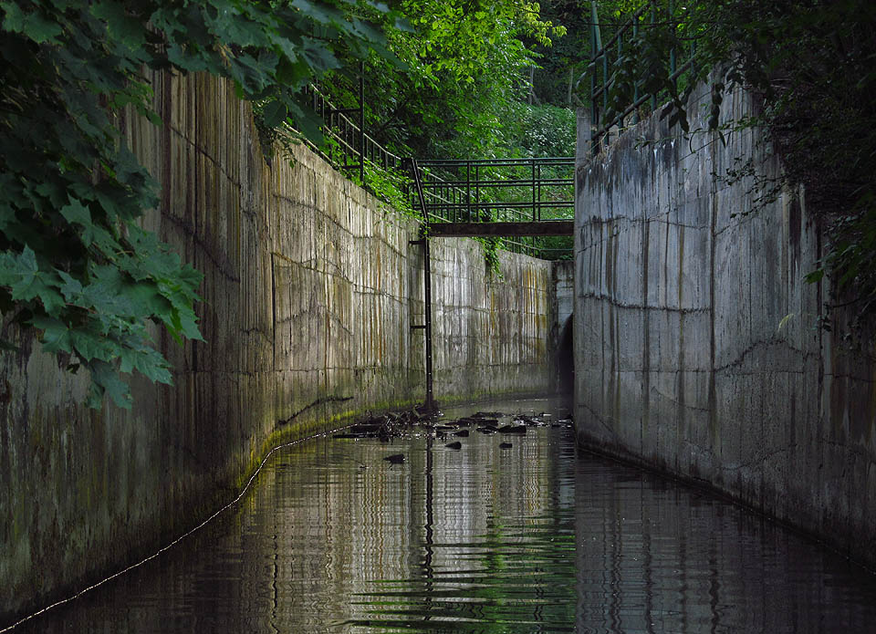 Mezi nepřístupnými betonovými stěnami utopenými v džungli se líně valí kalná a mrazivá voda. Nad ní se vznáší opar, jak teplý letní vzduch kondenzuje v chladu vytékajícím ze štoly.