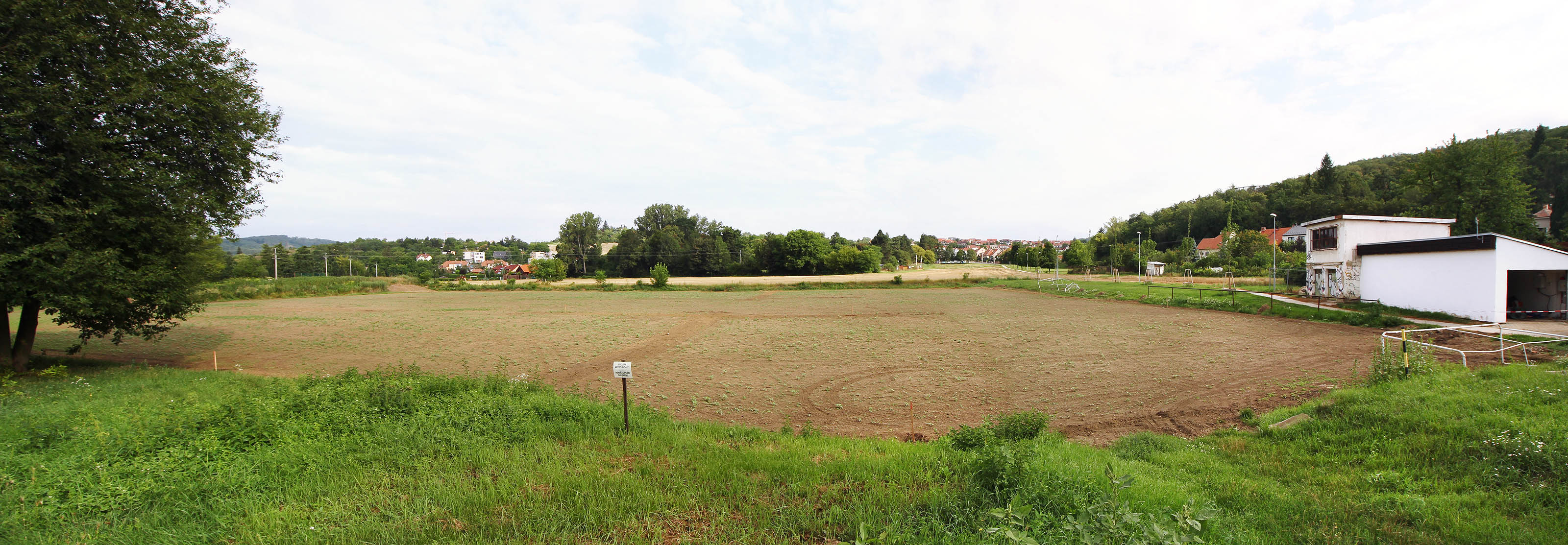 Tak vypadalo místo zamýšlené ke stavbě úpravny vody v roce 2017. Nivu nad soutokem <a href="/Tema/Svratka">Svratky</a> s Mniším potokem pokrývá zorané fotbalové hřiště a pole. V popředí na fotce se měly nacházet rozlehlé skládky písku pro pozvolné filtry, samotné filtry by pak stály na rozhraní žlutého pole a lesa v dálce. Na místě domů v pozadí by stála budova s usazovacími nádržemi a hrubocezy, za bílým domem vpravo pak hlavní vodojem a strojovna čerpací stanice.