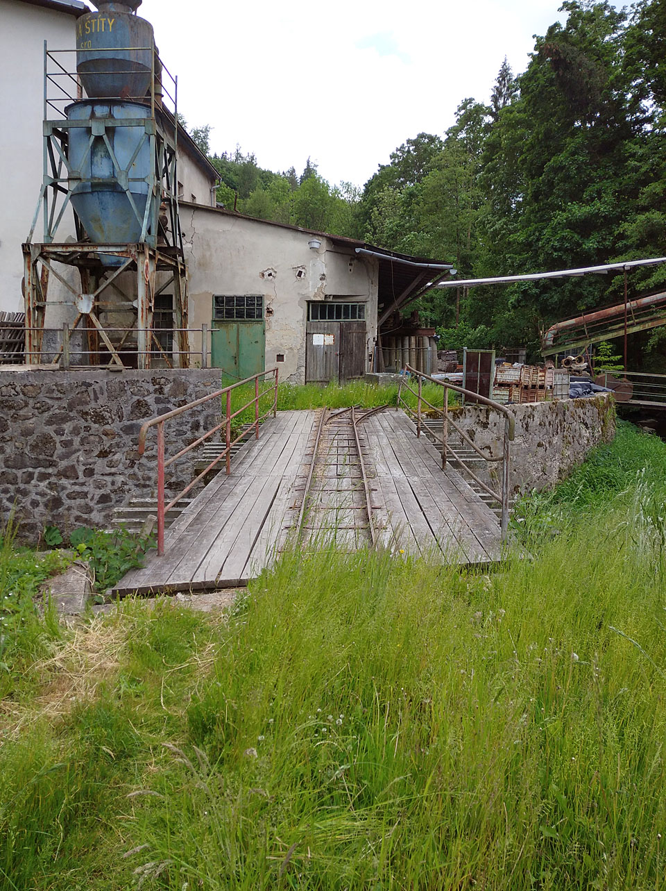 Středobodem drážky je železniční most s dřevěnou mostovkou, spojující dvě části pily na protilehlých březích říčky Březné.