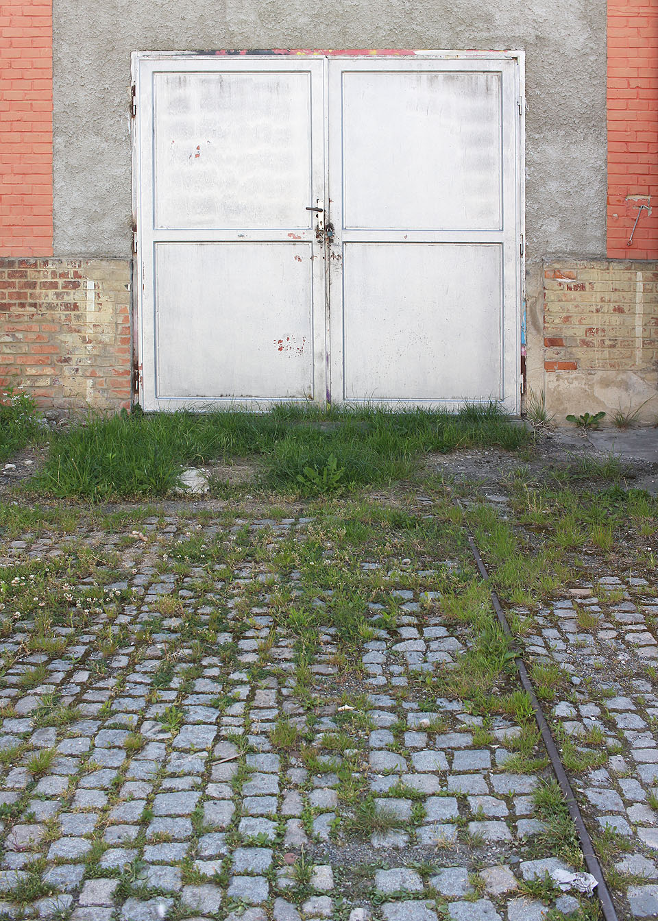Koleji vycházející z vrat v budově už zbyla jen jediná kolejnice.