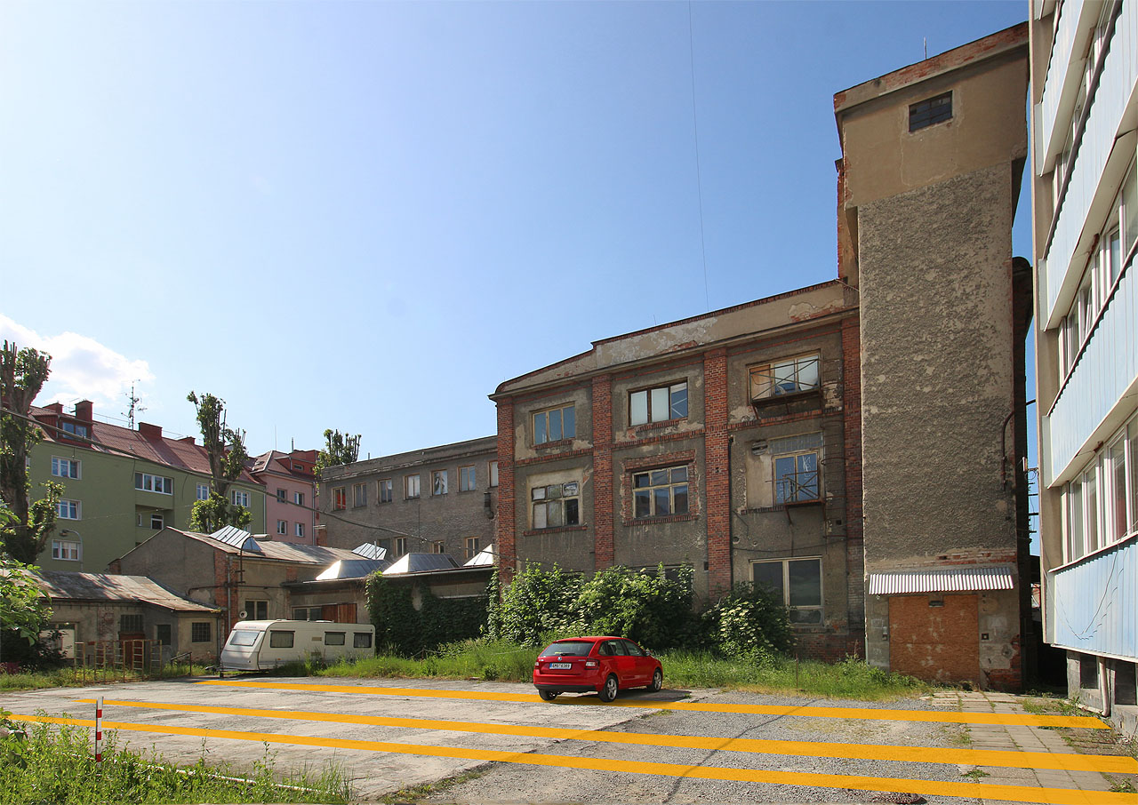 Oranžově jsou do fotografie továrního dvora zakresleny trasy tří odboček z hlavní větve drážky tak, jak tu vedly v 2. polovině 20. století. Dnes po nich nezbylo vůbec nic.