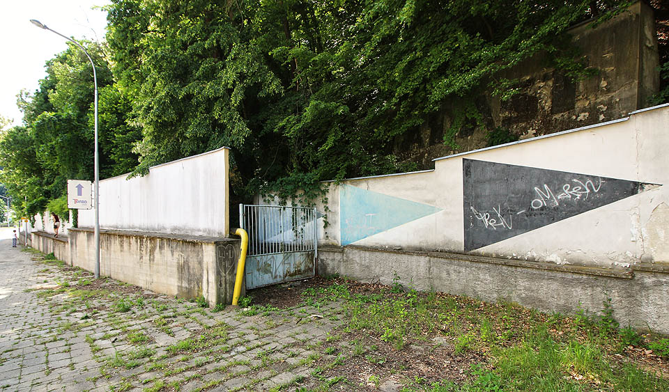 Hlavní vstup je nenápadně ukryt za zdí s reklamními nápisy. Kdysi ji zdobil nápis „Staletá práce adamovských kováků“, později změněný na „tradice, budoucnost, prosperita“ a nakonec přetřený úplně. Co na to říkají kováci, se nám zjistit nepodařilo. Nápis ADAST však vykukuje z hlubiny lesa dál, zániku firmy navzdory.