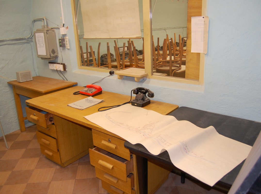 Odsud by v případě útoku na <a href="/Tema/Adamov">Adamov</a> probíhalo velení tomu, co zbylo ze strojíren a města okolo nich. Dva telefony na stole a štáb telefonistů za skleněnou přepážkou, žádné počítače, žádná potrubní pošta.