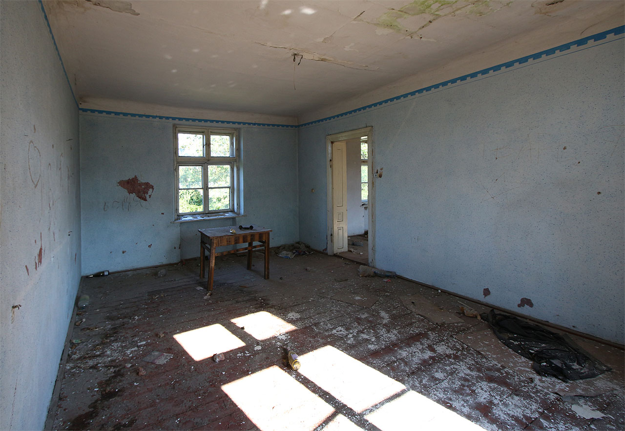 Vybavení je už dávno pryč. Zůstal jen stůl a na něm dvě utržená telefonní sluchátka.