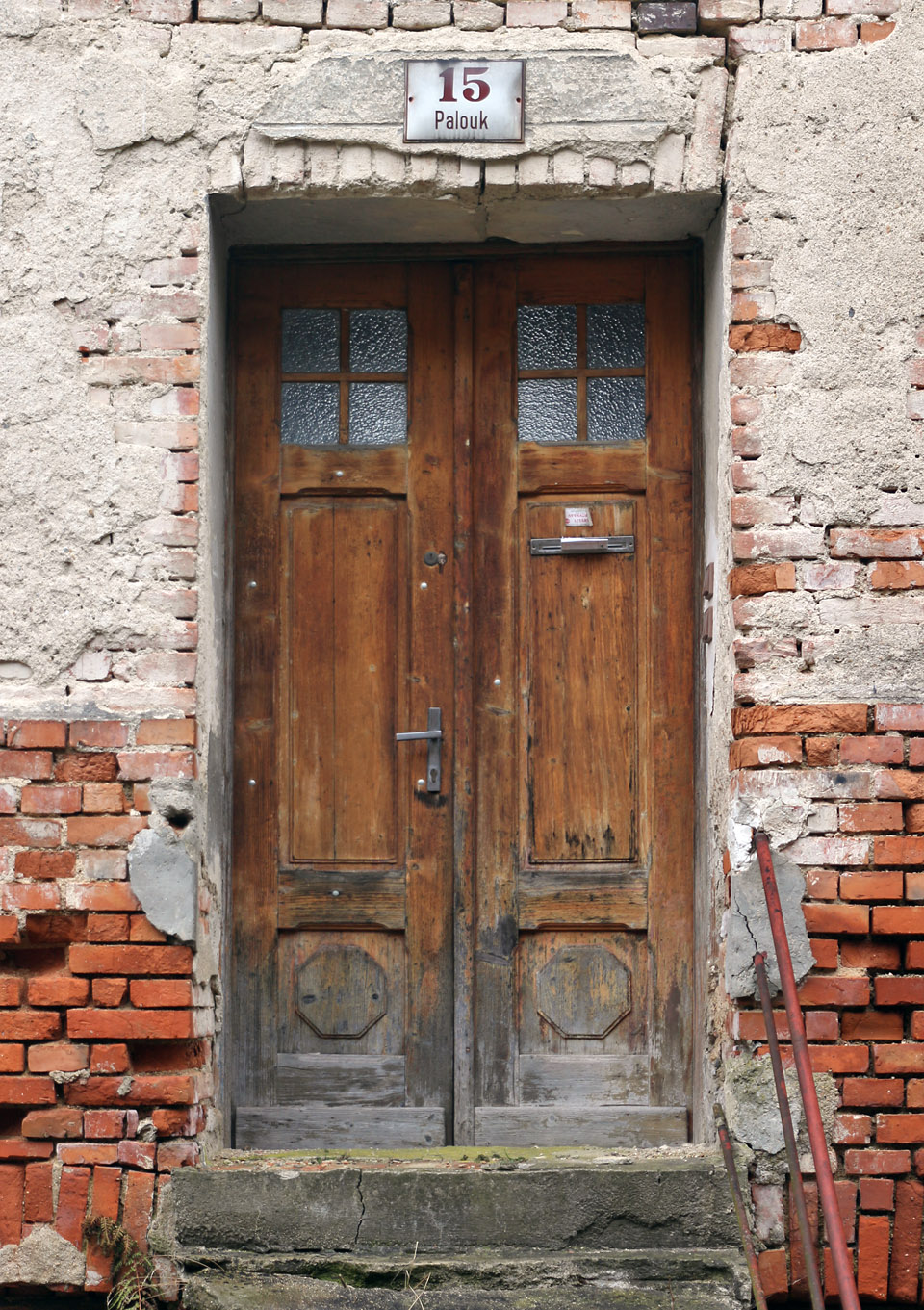 Vstupní dveře domu Palouk 15. Představujeme si osamělého majitele, který se celý život snažil o opravu vily, kterou ale nedokončil a vila byla nakonec zdemolována.