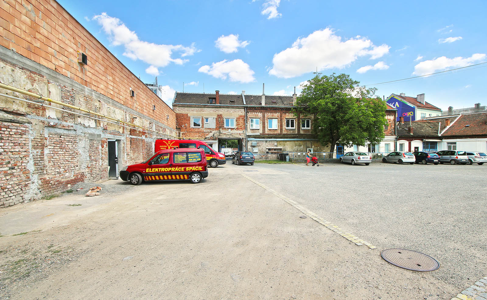 Pohled z opačné strany: vlečka vedla podél zdi vlevo až k bráně. Přibližně v místě kanálového poklopu se dělila na dvě koleje pro nakládku a vykládku zboží. Na opačné straně brány se už nachází hlavní komárovská tepna - Svatopetrská (dříve Petrohradská) ulice.